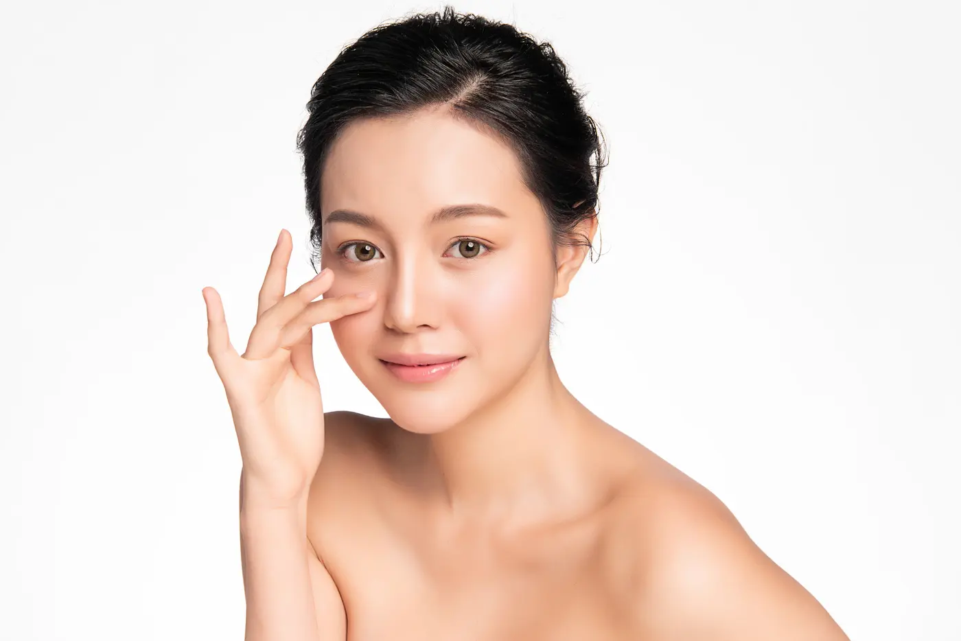Woman with clear skin touching face, showcasing skincare results.